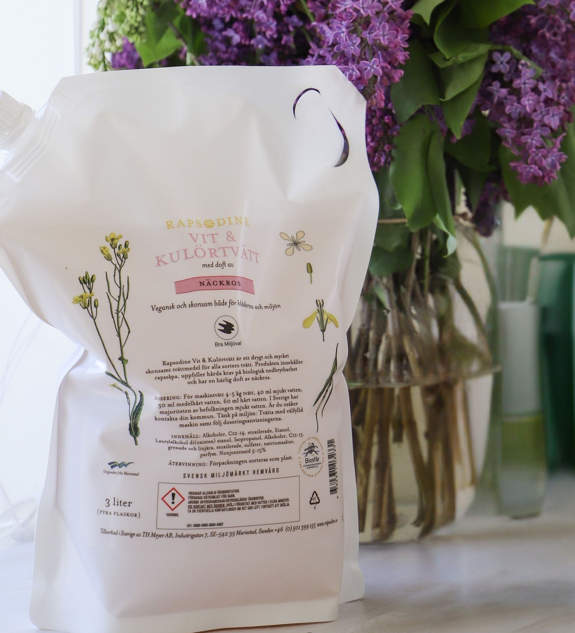 Rapsodines refill för vit- och kulörtvätt med doft av näckros i naturlig tvättmiljö med lila blommor
